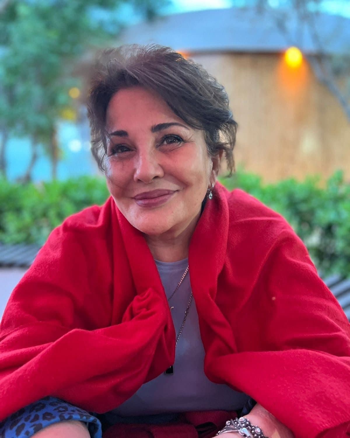 Sığınacağın sədri Mehriban Zeynalova qırmızı şala bürünüb, yaşıllığın fonunda gülümsəyir